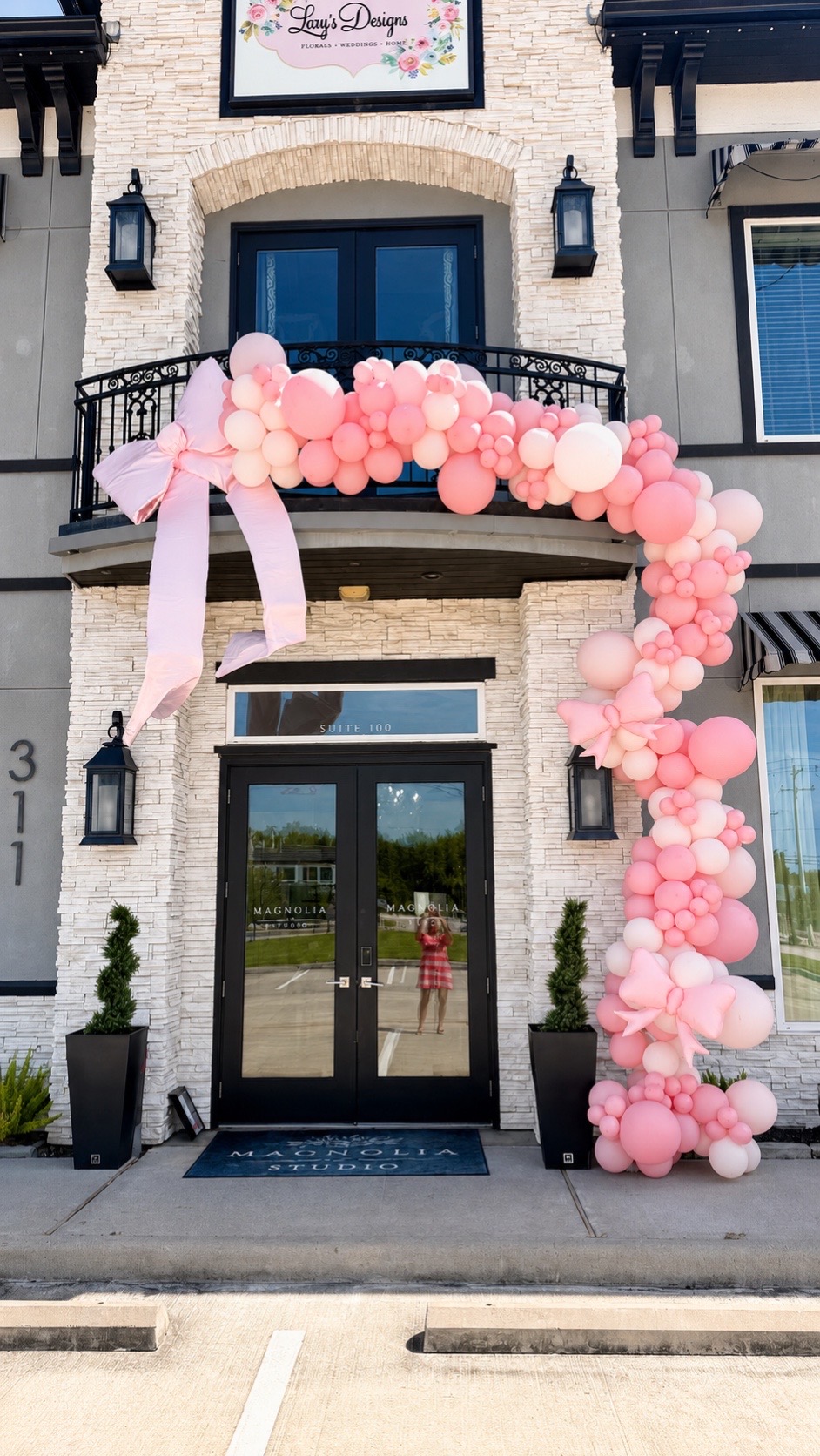 Pink balloon garland and bows arching over the Magnolia Studio entrance for a baby shower