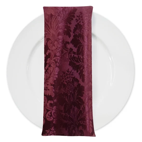 The burgundy damask napkin on a white plate
