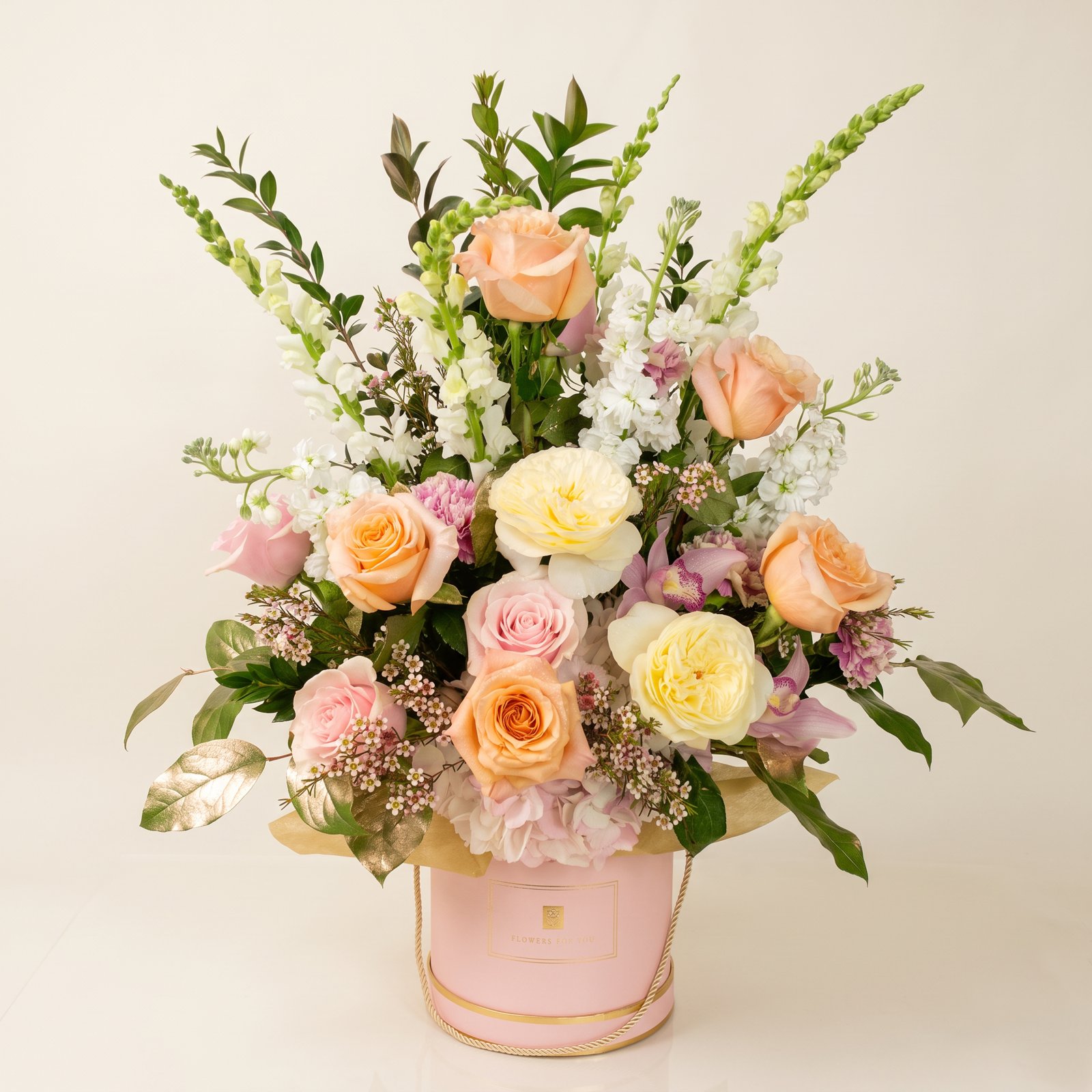 Peach and blush roses with snapdragons in a pink hat box