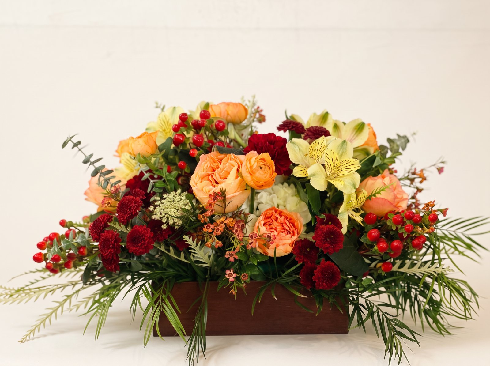 Garden roses, burgundy mums and red berries in a wood box
