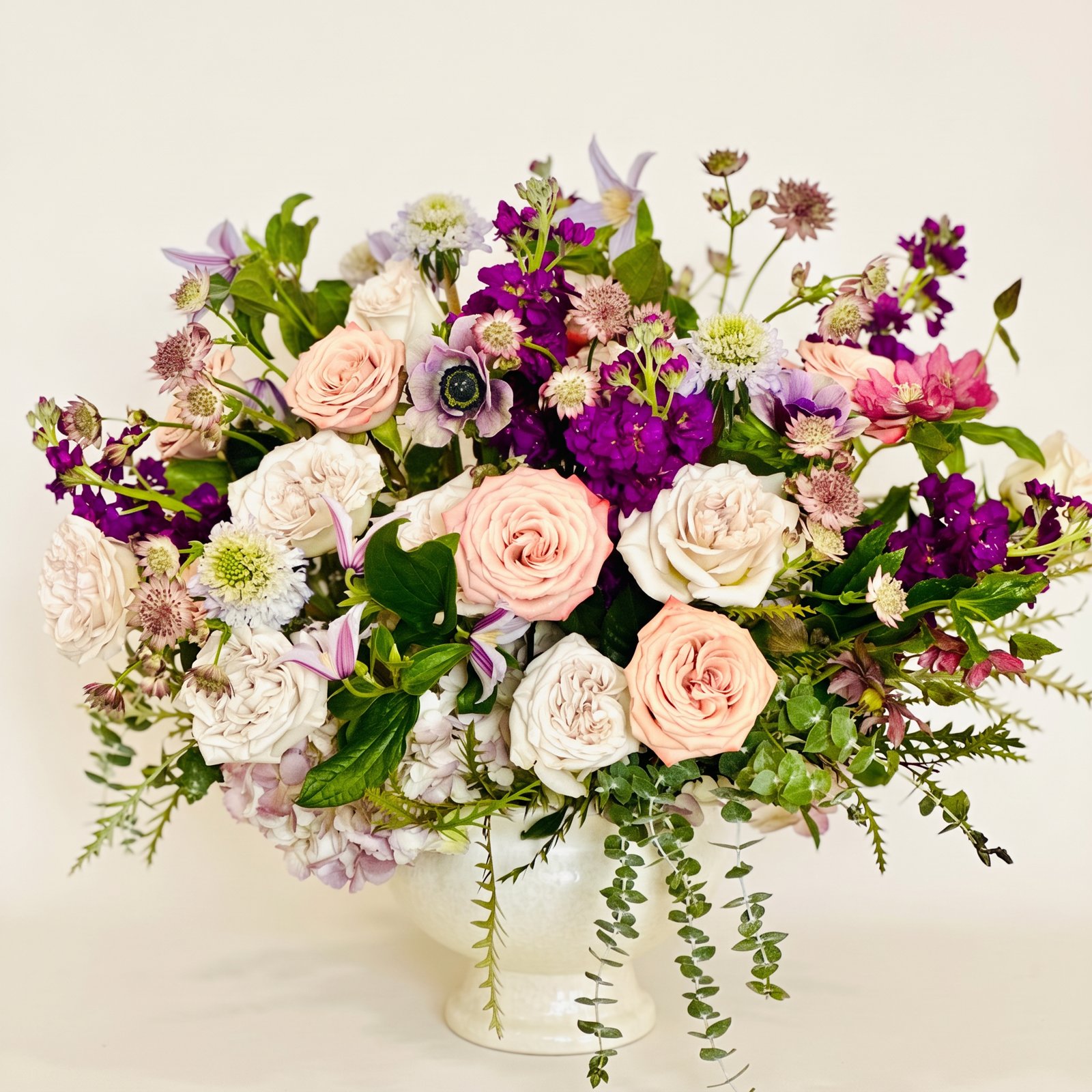 Garden roses, stock and anemones in an ivory footed vase