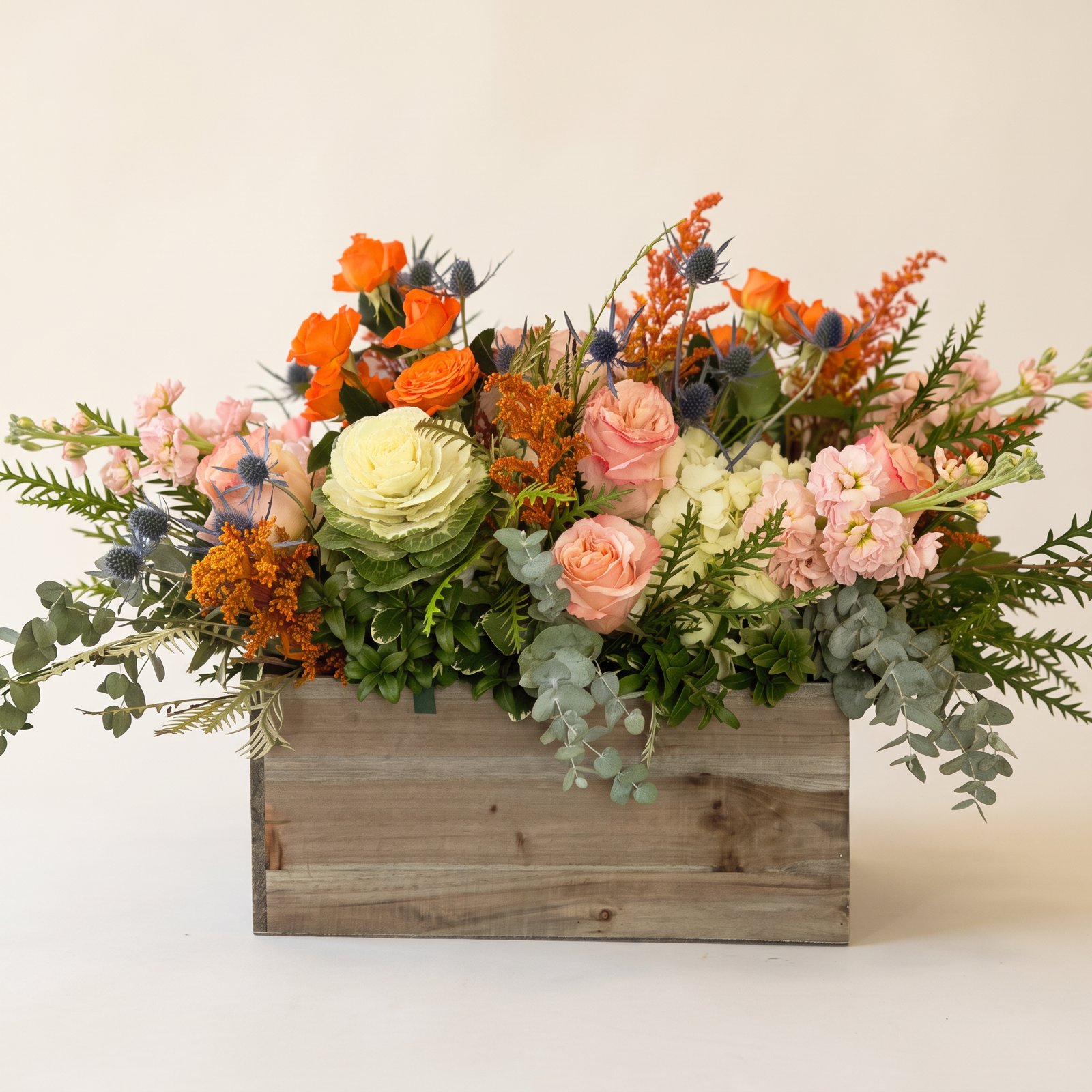 Peach roses, ornamental cabbage and eucalyptus in a rustic wood box