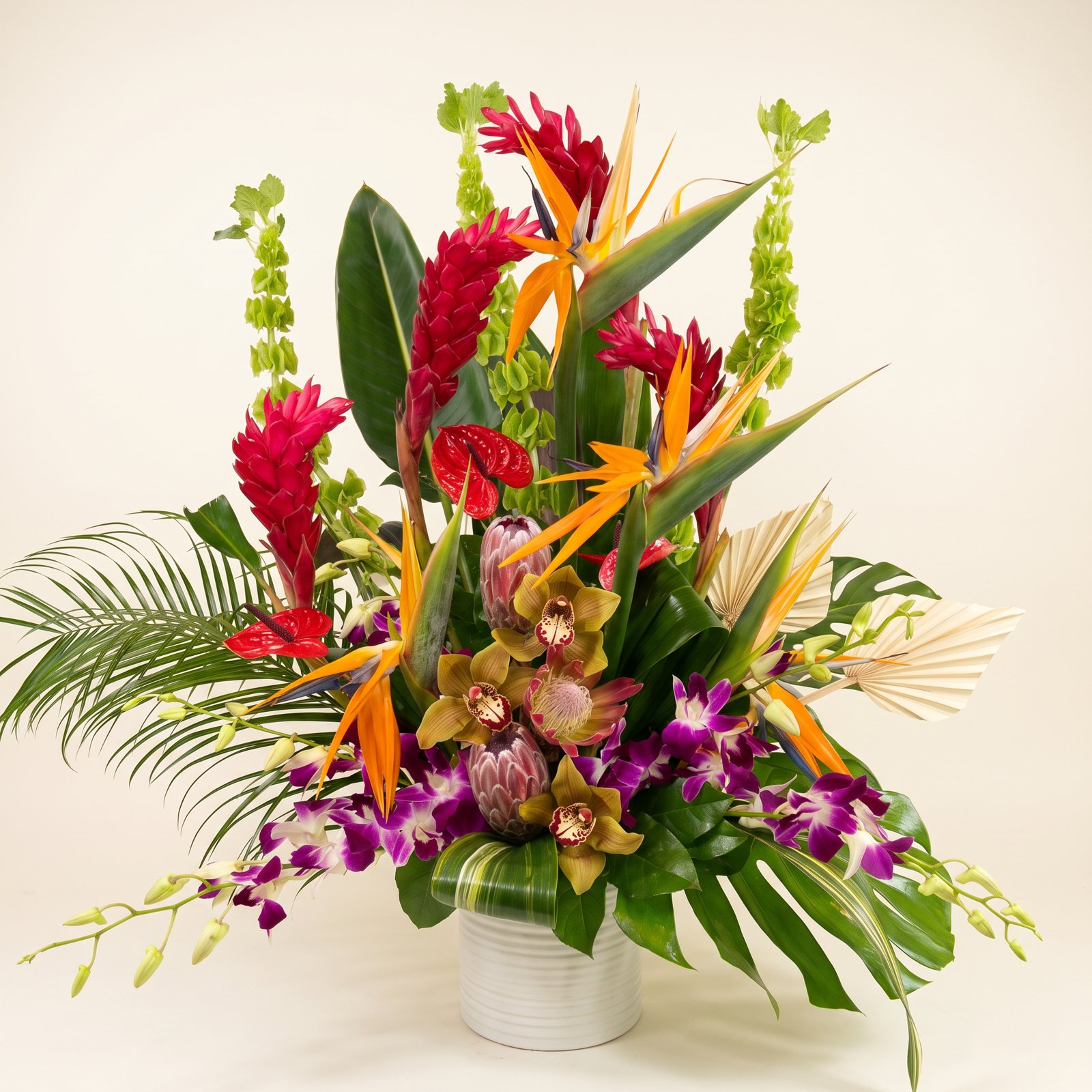Tropical birds of paradise, ginger and orchids in a white vase